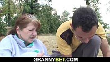 A guy tends to Granny's damaged busty hairy pussy.