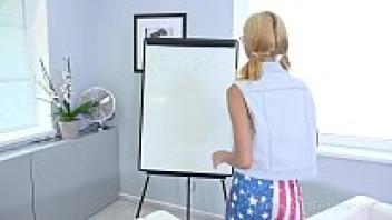A blonde wearing glasses is seen writing on the white board by the cameraman.