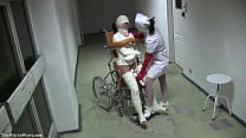 A wheelchair-bound patient wearing a straitjacket and with broken legs - TheWhiteWard.com