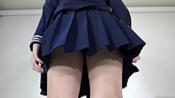 A girl removing her cheerleading uniform while wearing a skirt