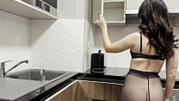 In the kitchen, a gorgeous, seductive, petite blonde wearing shiny black pantyhose without underwear