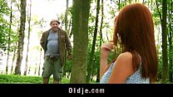 Strange elderly woodland man who adores a redhead in the woods